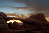 - A Hiker Traversing Double O Arch at Sunset, Arches NP -